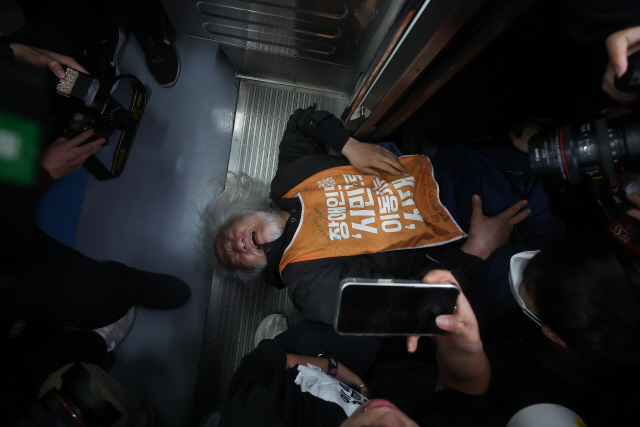 박경석 전국장애인차별철폐연대(전장연) 대표가 21일 서울 지하철 4호선 혜화역에서 제62차 '출근길 지하철 탑니다' 시위를 벌이던 중 이를 저지하던 서울교통공사 관계자와 충돌하며 넘어져 있다. 이날 오전 9시 30분 기준 4호선 혜화역 하행선은 이 시위로 무정차 통과중이다. [연합뉴스]